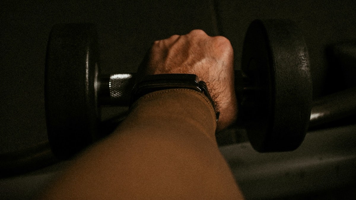 a person's hand holding a barbell in a dark room